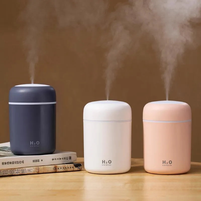 Pink, white, and navy blue USB-powered mini desktop humidifier with water tank and mist spray.