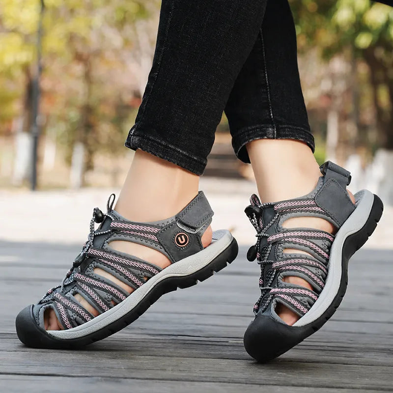 Women's black leather mesh toe box sandals with elastic band and rubber sole on a beach