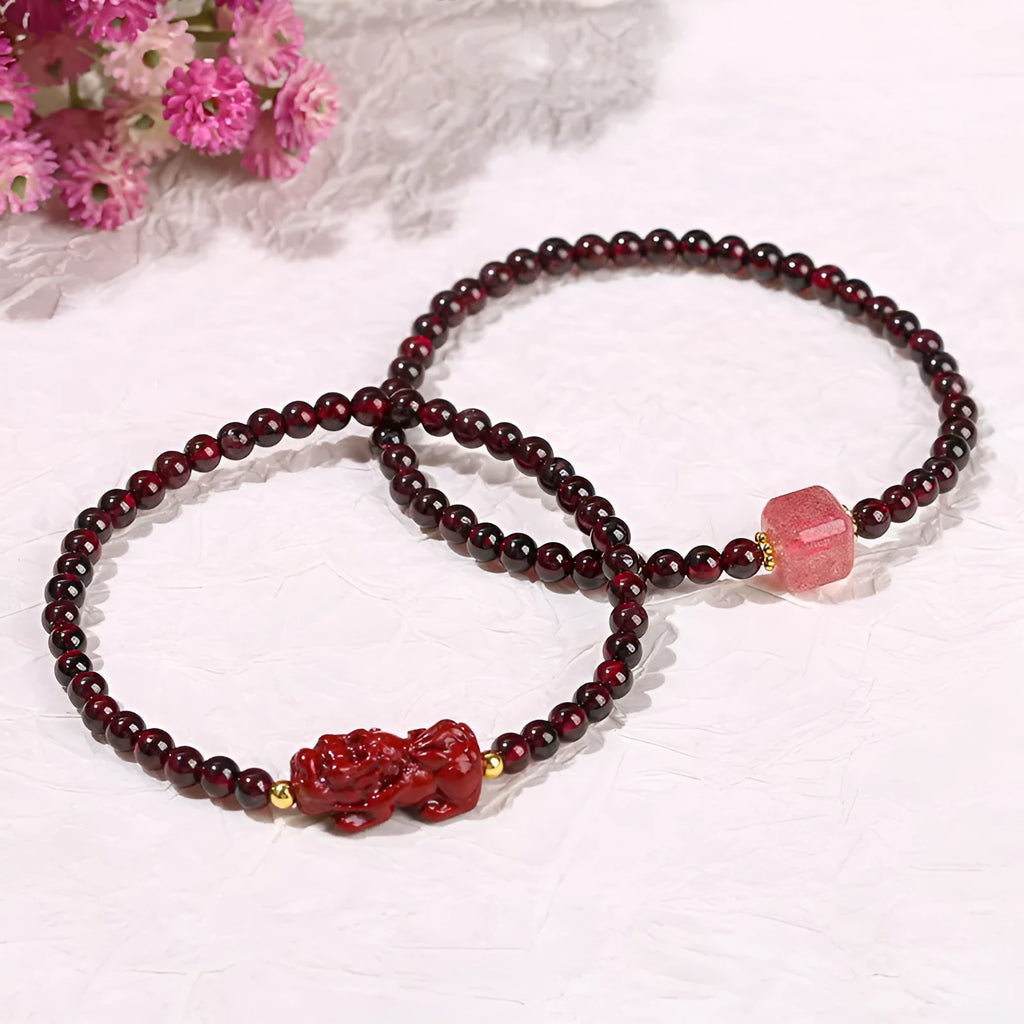 Geometric square garnet bracelet with carved Pixiu and strawberry quartz accents on a purple sand background.