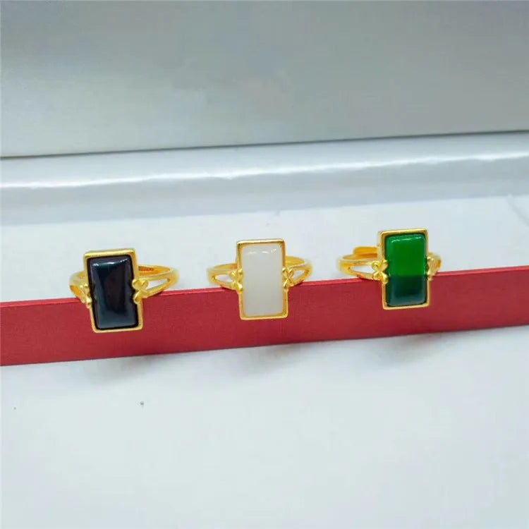 A gold-plated brass ring with an adjustable band and a central green artificial gemstone, in a national style.