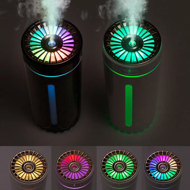 Black and white portable USB rechargeable car humidifier with colourful LED lights on a desk.