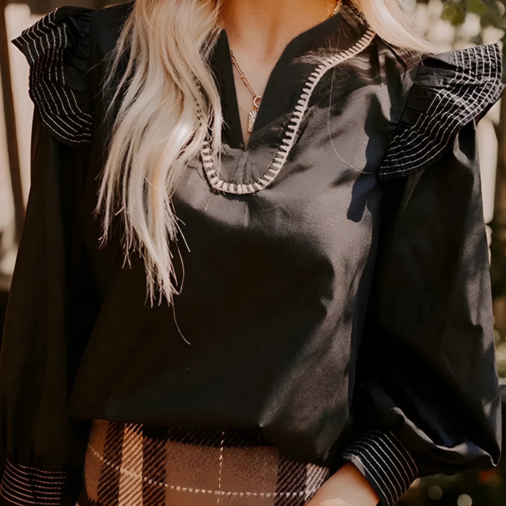 Black women's V-neck blouse with ruffle detailing on the long sleeves and contrast colour stitching.