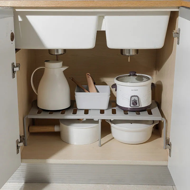 White telescopic kitchen storage rack with adjustable height on a countertop