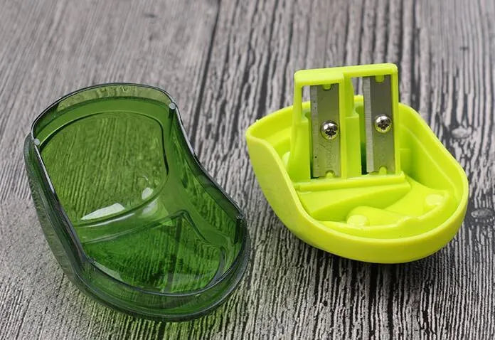 A single-hole plastic pencil sharpener in a random colour, showing its closed design.