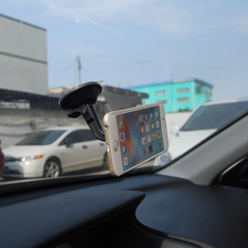 Black magnetic car phone holder with 360-degree rotating bracket mounted on a car dashboard.