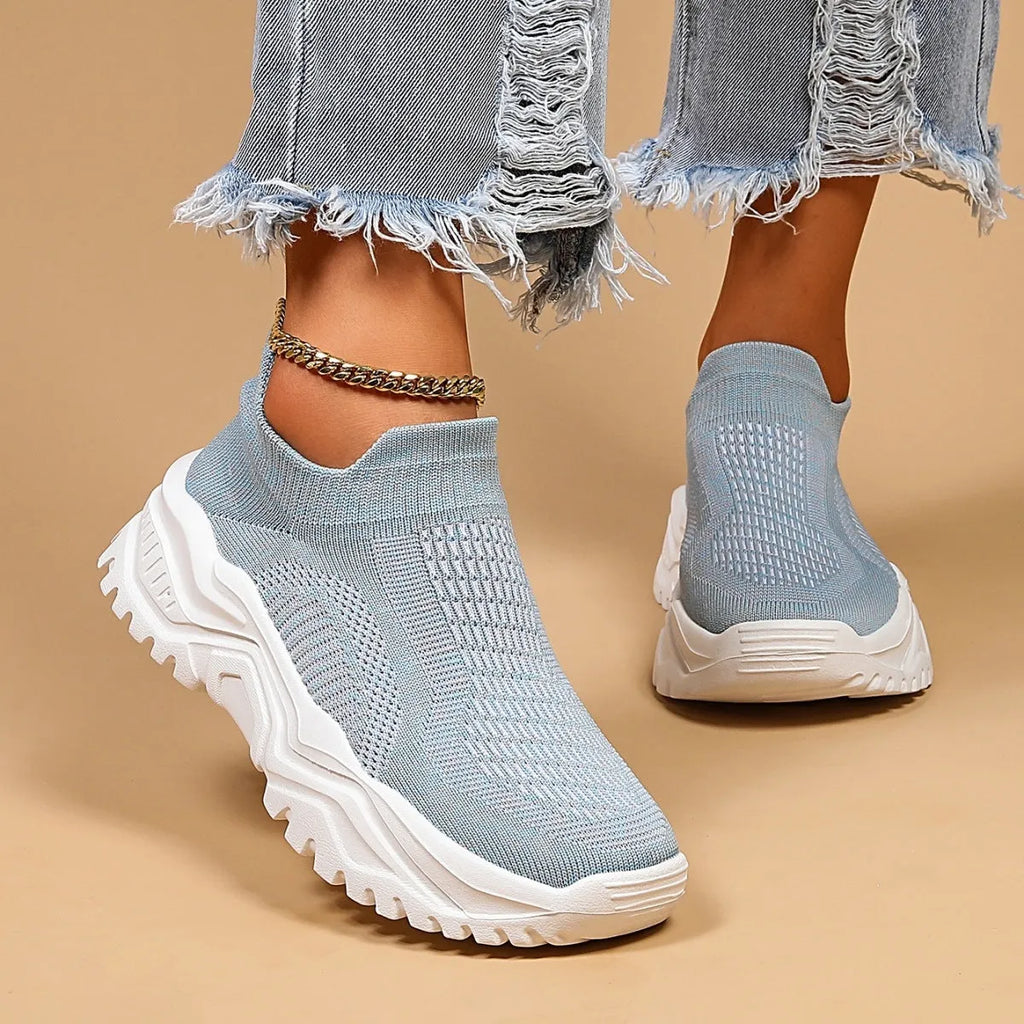 Light blue women's mesh slip-on sports shoes with a round toe and mid heel on a white background.