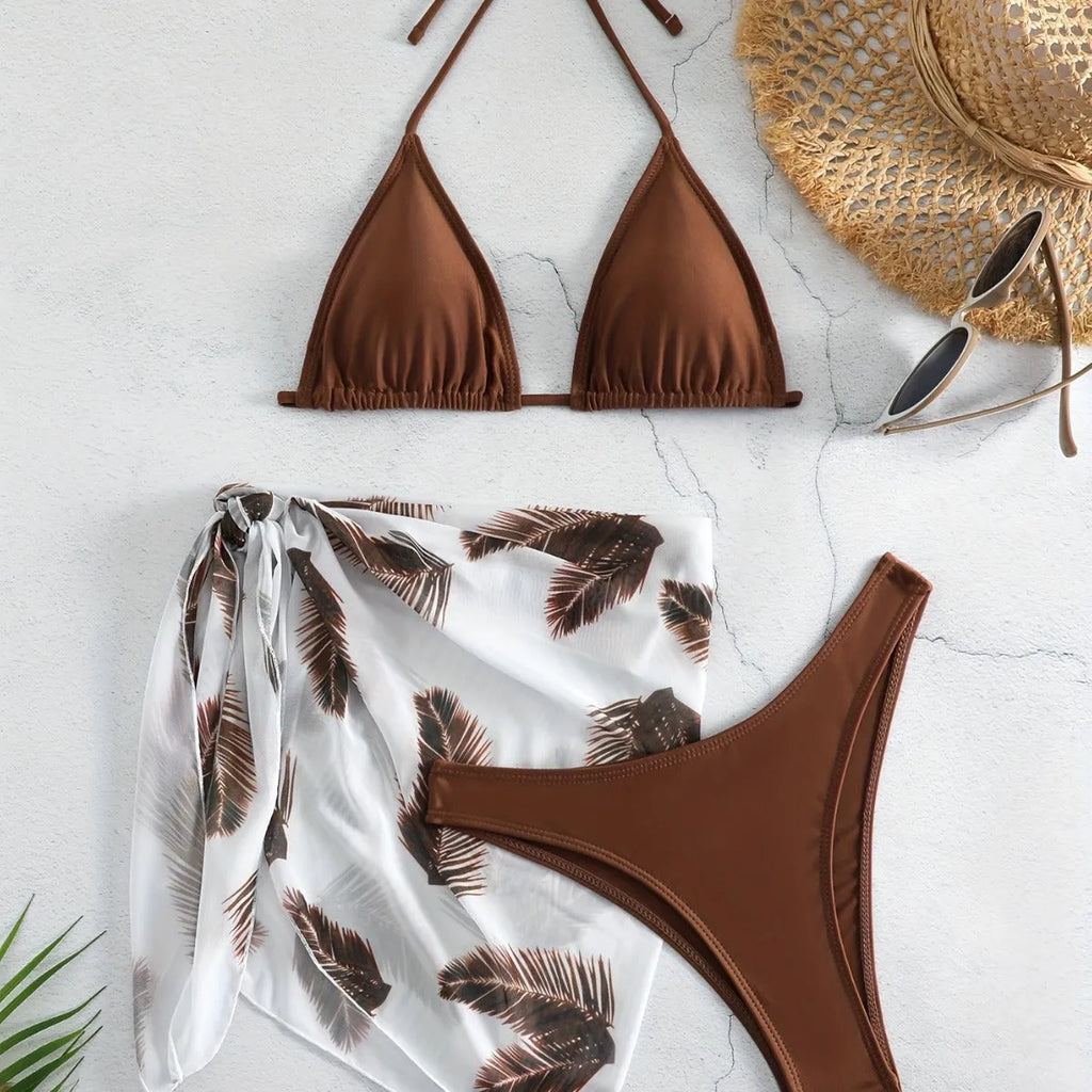 Women's orange three-piece bikini swimsuit set with a matching printed gauze skirt laid flat.