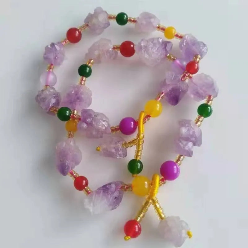 Close-up of a women's bracelet with natural shaped amethyst beads and a silver fu charm on a white background.