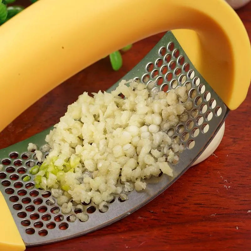 Stainless steel garlic press with ergonomic black handle on a kitchen counter.
