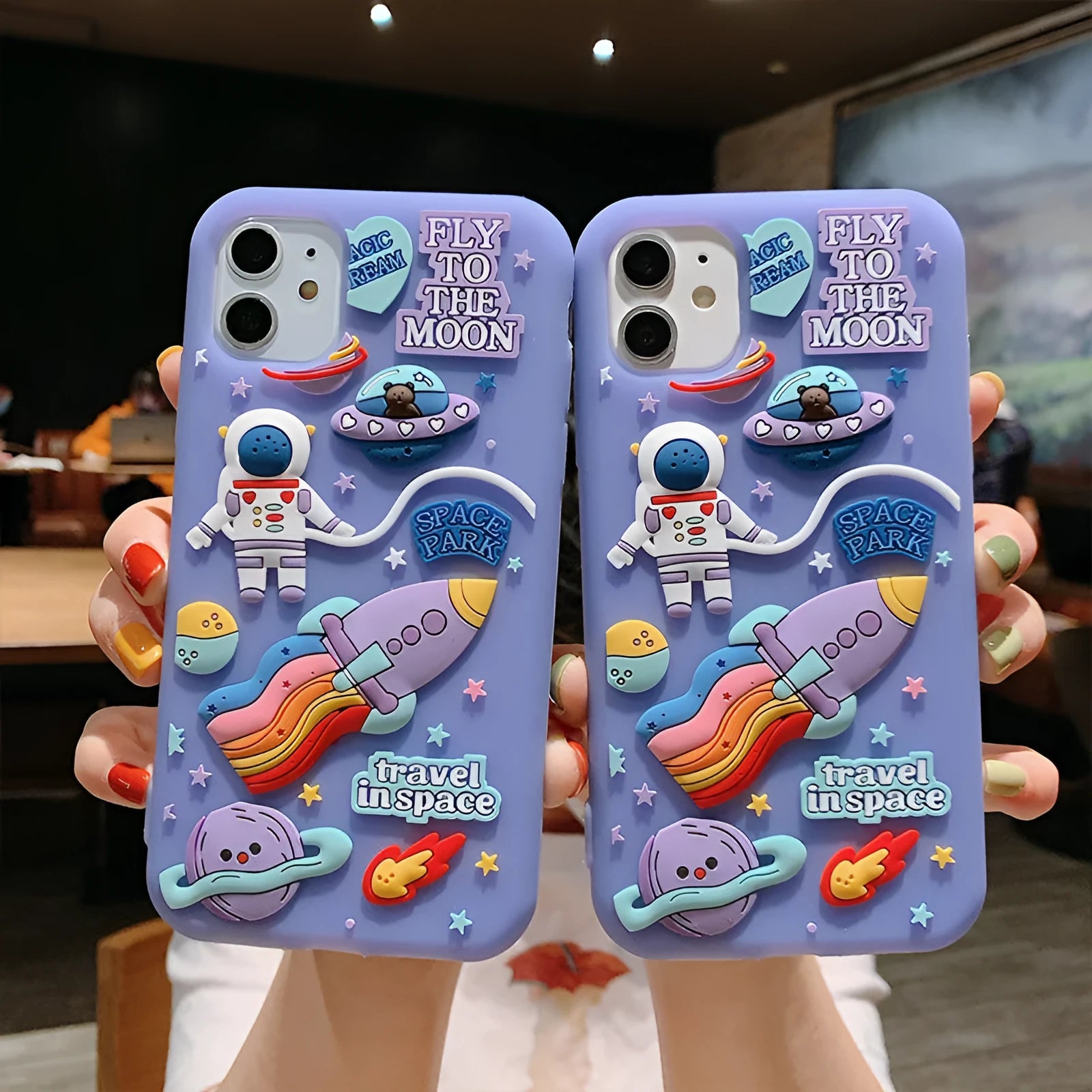 Purple silicone iPhone case with a cartoon astronaut design, shown fitted on a phone.