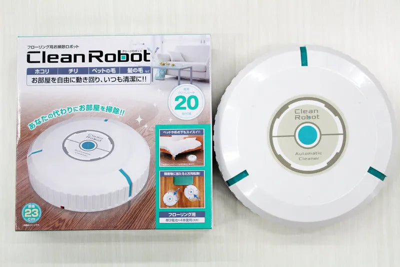 Black automatic sweeping robot on a wooden floor next to its packaging.