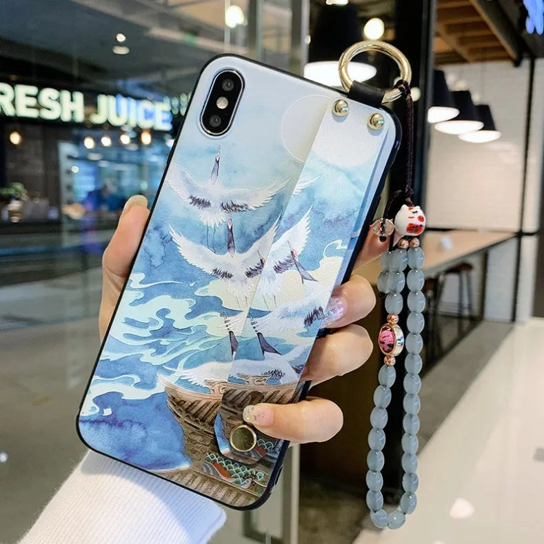 Rose flower design wrist strap phone case for Apple iPhone models on a table.