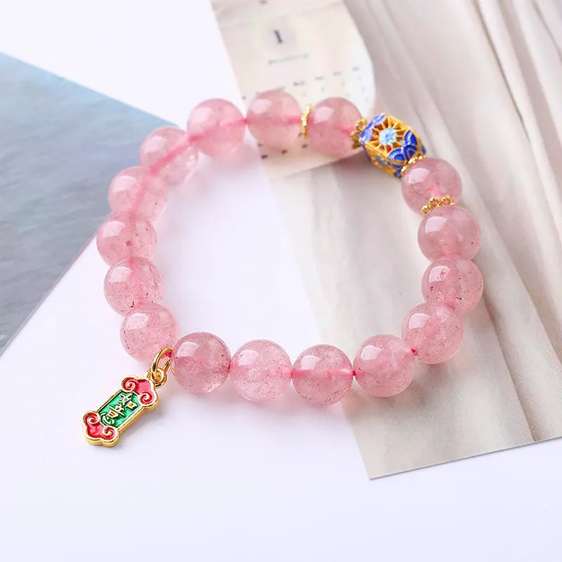 Pink strawberry quartz crystal bracelet with hand-woven beads, Ruyi charm, and letter charms.