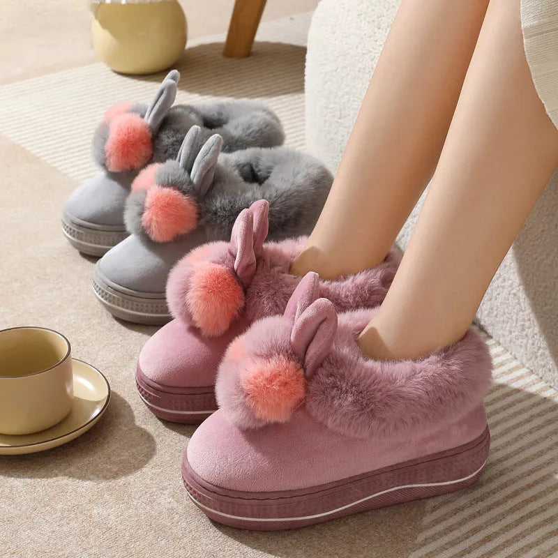 Grey plush high-heel winter slippers with a thick TPR sole on a wooden floor.