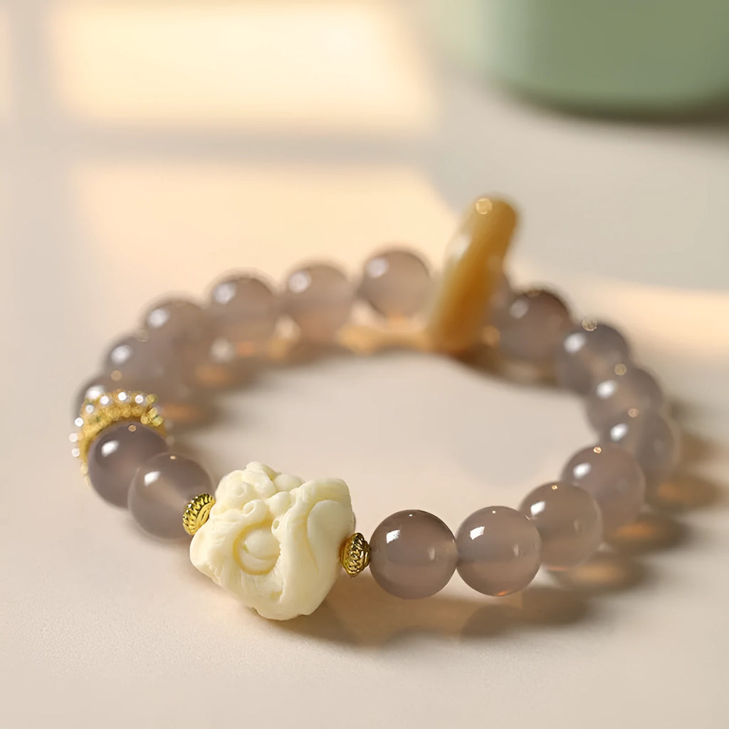 Hand-woven grey agate bracelet with 10mm round beads and mellite decorative accents.