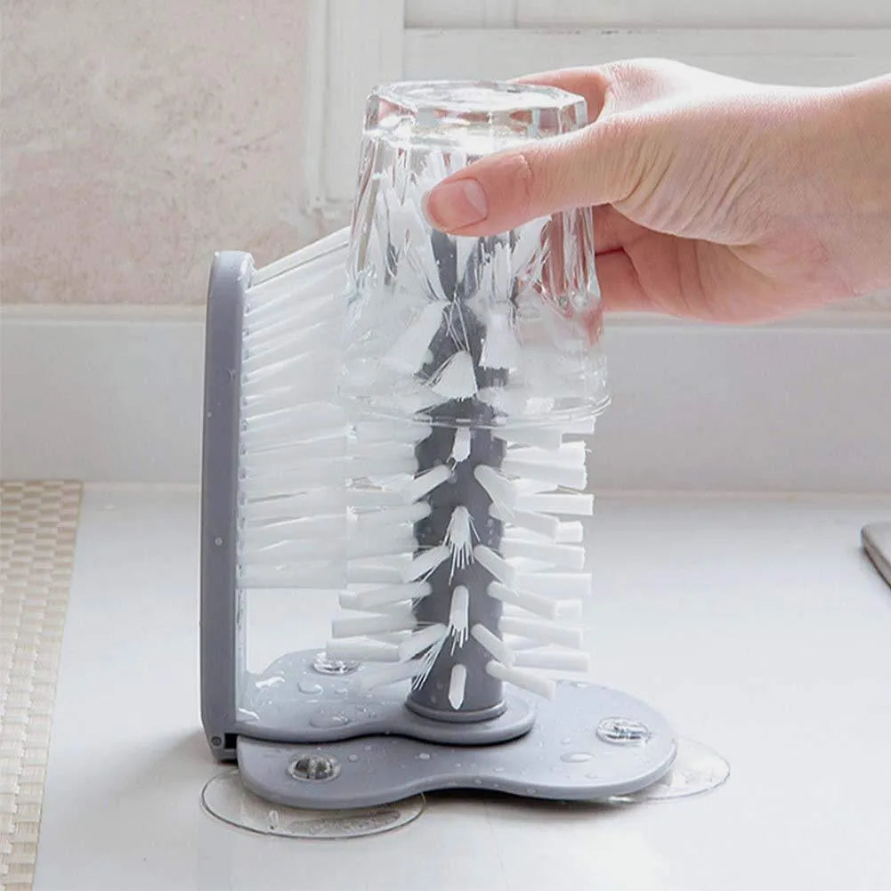Grey 2-in-1 cup scrubber with double-sided bristles and three suction cups on a white surface
