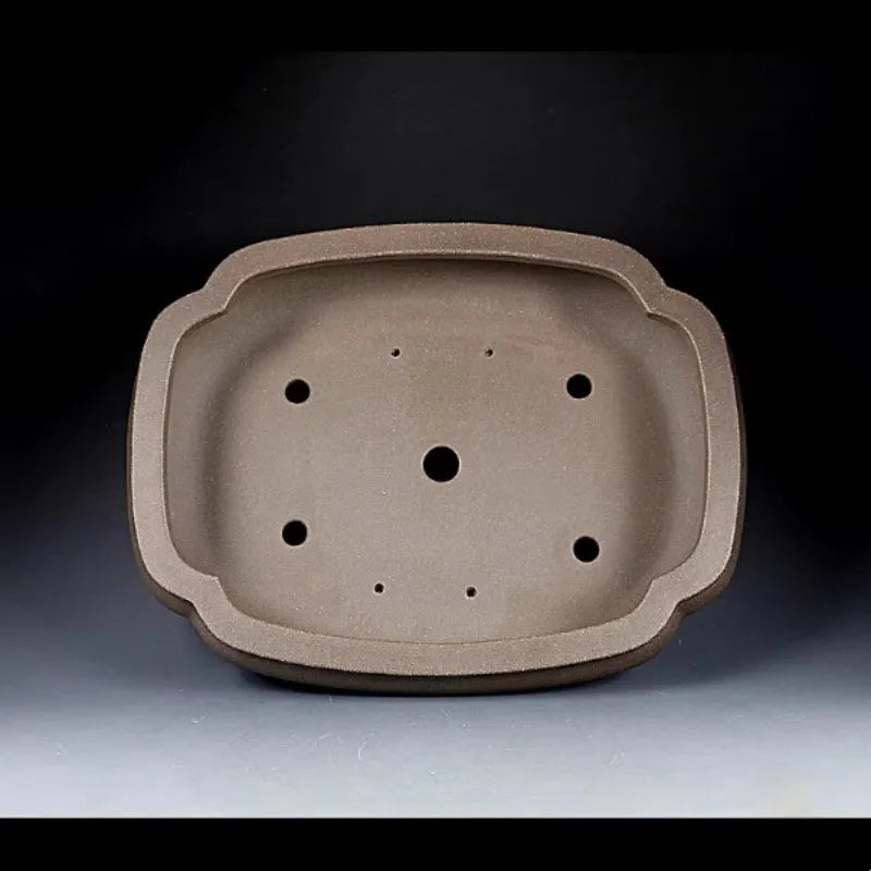 Handmade antique papaya-shaped purple clay flower pot on a table.