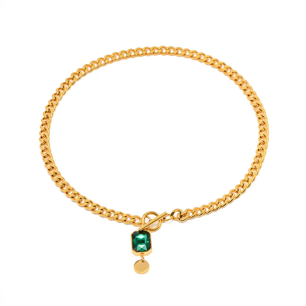 Gold titanium steel pendant necklace with geometric design and emerald zircon centre on Cuban link chain