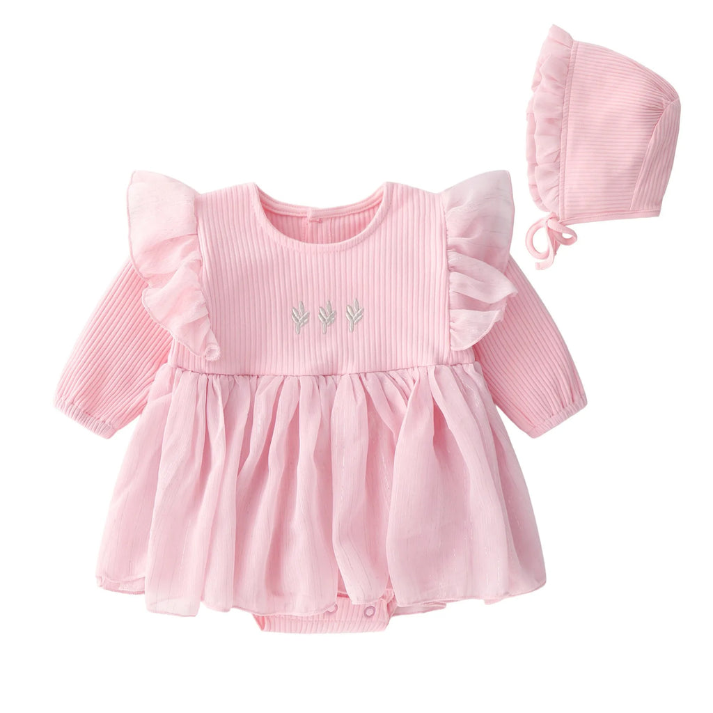 A baby girl wearing a fluffy cotton princess dress in pink, for a christening or birthday.