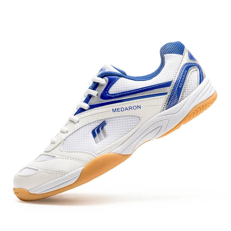 White and blue table tennis sneakers with synthetic leather upper and rubber sole on a court surface.