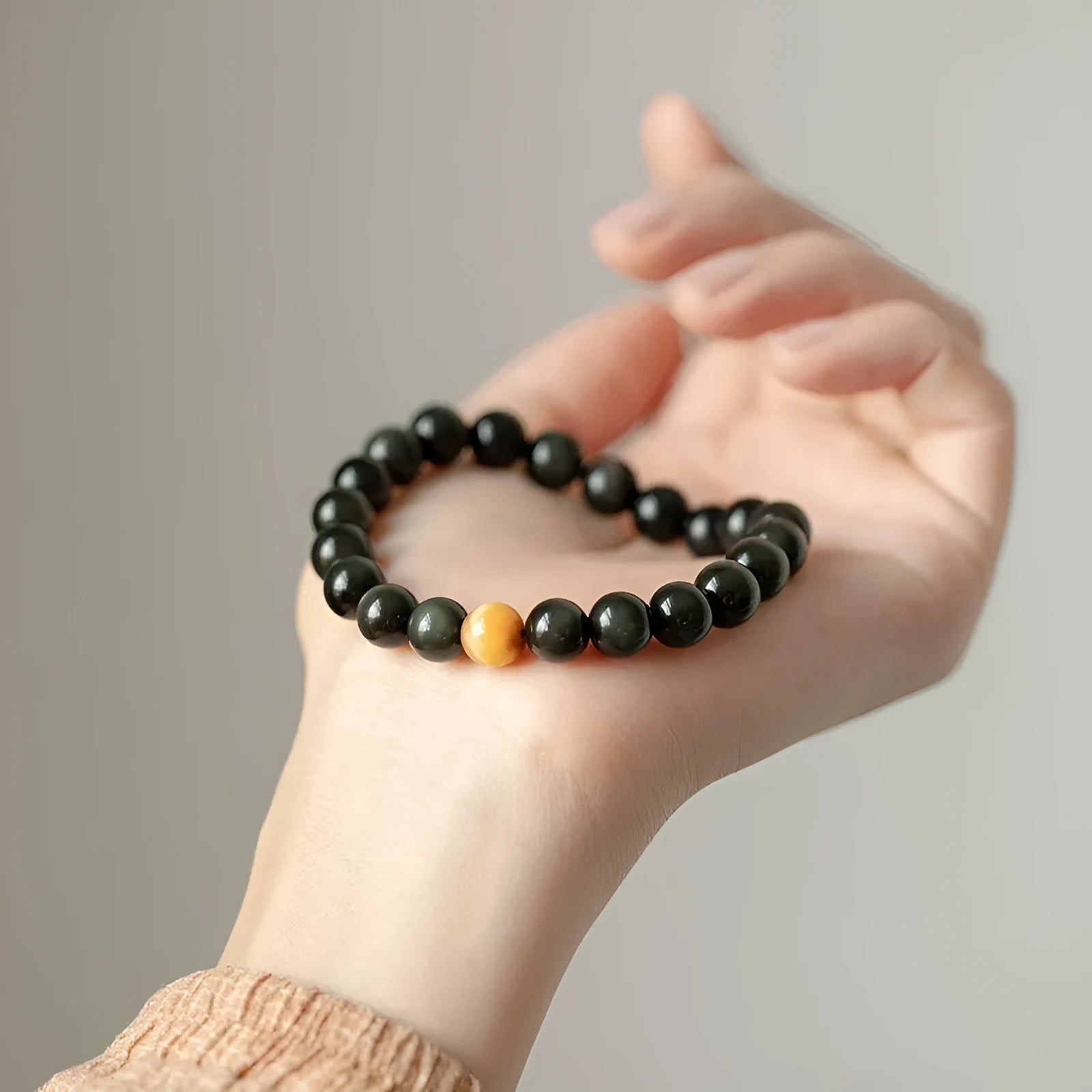 Natural black obsidian geometric bead bracelet on an adjustable string, showing 10mm bead size.