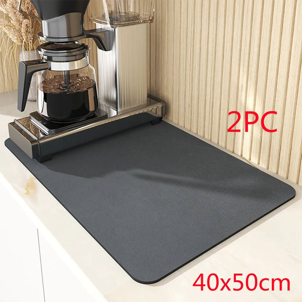 Square black kitchen drain mat with rubber backing placed under coffee machine on countertop