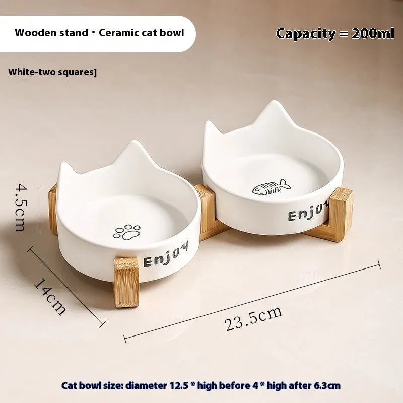 Porcelain cat bowl with cat ear handles in a wooden anti-tumble frame, showing paw print design.