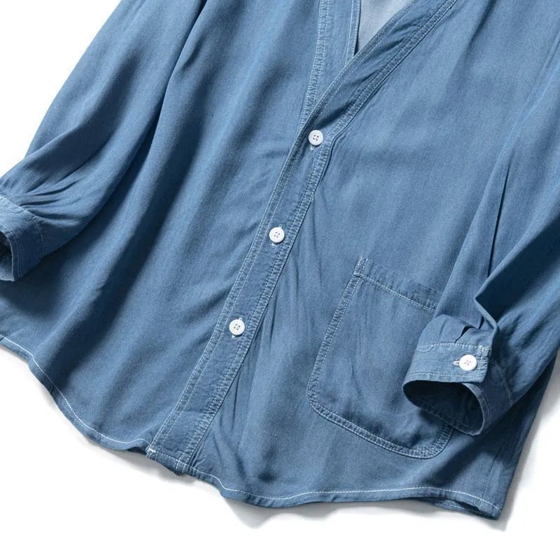 Men's dark blue V-neck denim coat with three-quarter sleeves showing loose fit and pocket detail
