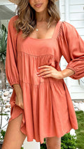 Girl in an orange red backless dress with a square collar and puff sleeves, showcasing the A-line skirt.
