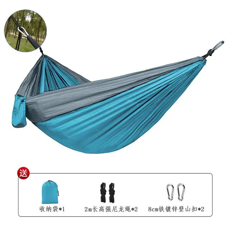 Blue nylon parachute cloth outdoor hammock hung between trees, showing its length and width.