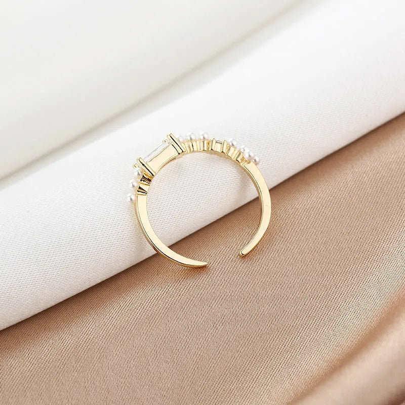 Gold alloy ring with square artificial gemstone inlay and diamond-cut surface, adjustable opening, on a white background