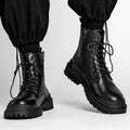 Men's black leather-look mid-top boots with a flat rubber sole on a neutral background