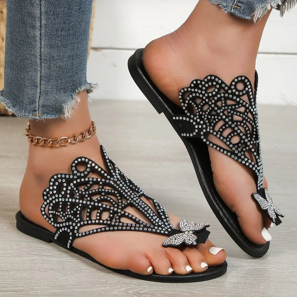 Women's black flip-toe sandals with rhinestone decorations and a hollow out design on a gold background.