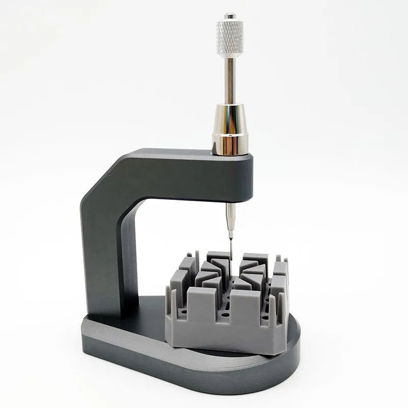 Silver tool steel press strap removal tool for watch and jewellery repair on a workbench.