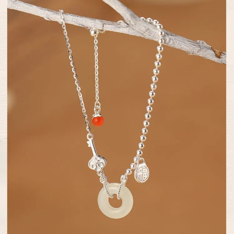 Women's silver bracelet with Hetian jade and a traditional Chinese peace buckle charm on a geometric link chain.