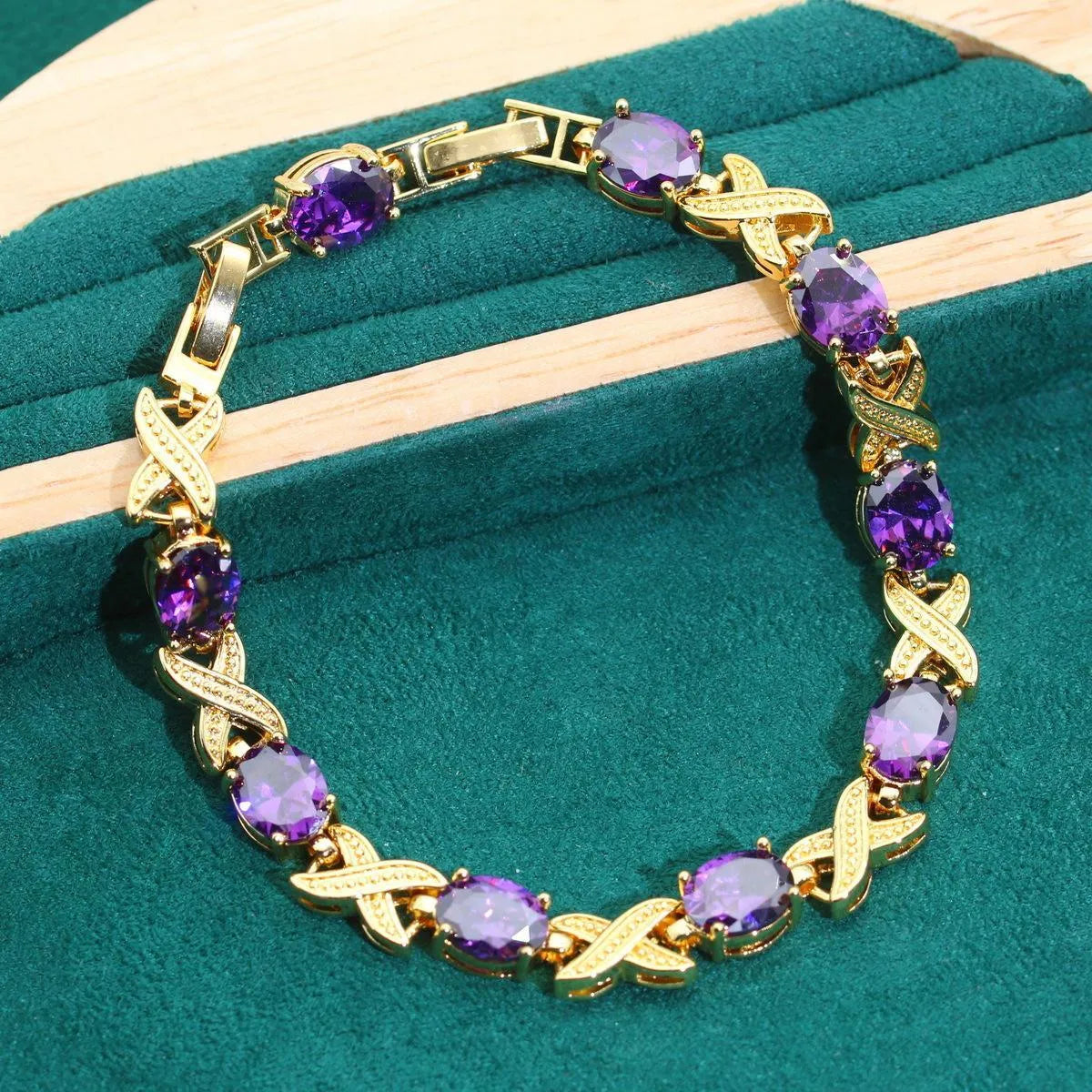 Gold plated necklace, earrings, ring, and bracelet set with blue cubic zirconia stones on a grey background.
