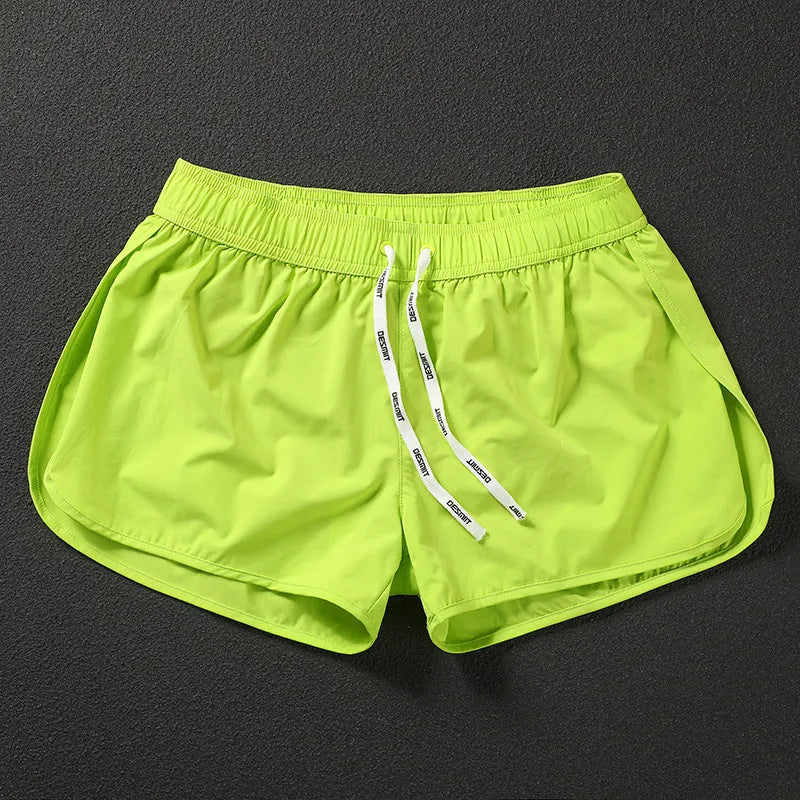 Men's loose orange red polyester beach surfing shorts with elasticated waist on a man