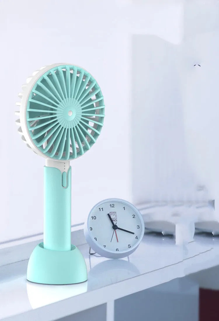 Blue handheld mini USB electric fan with three-speed control on a desktop.