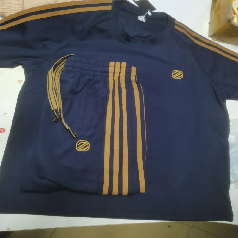 Man wearing a blue short sleeve polyester tracksuit set, showing the matching top and trousers.