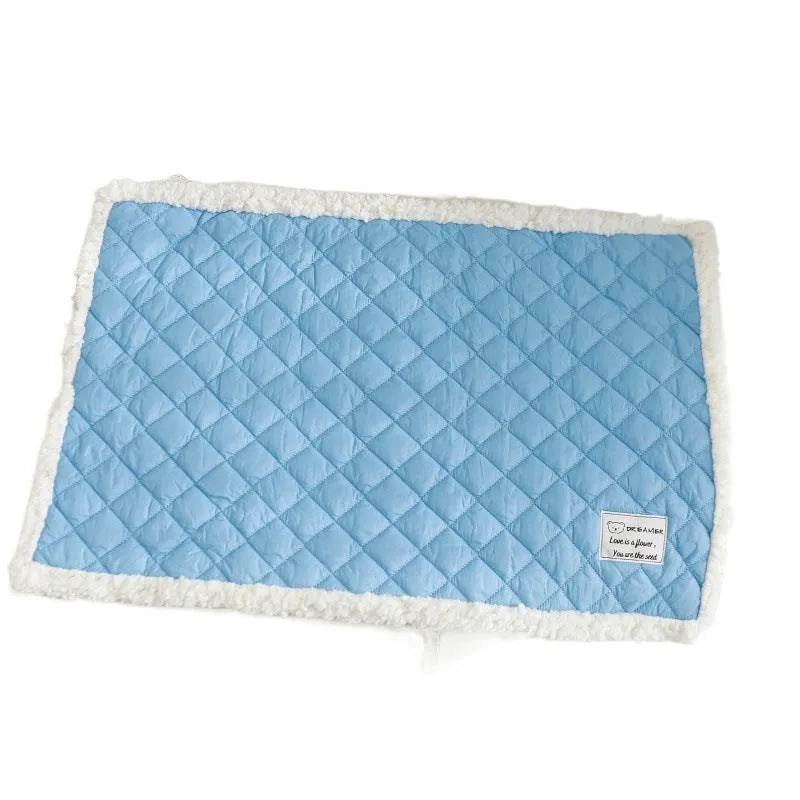 Blue quilted cloth pet blanket for cats lying flat, showing its rectangular shape and textured surface.