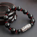 Hand-woven black agate dzi bead bracelet with 11mm geometry beads on a wrist.