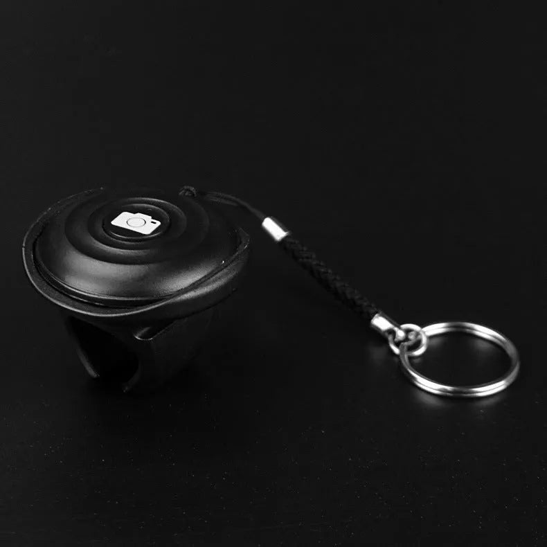 Black Snap Bluetooth remote control for wireless phone photography on a white background.