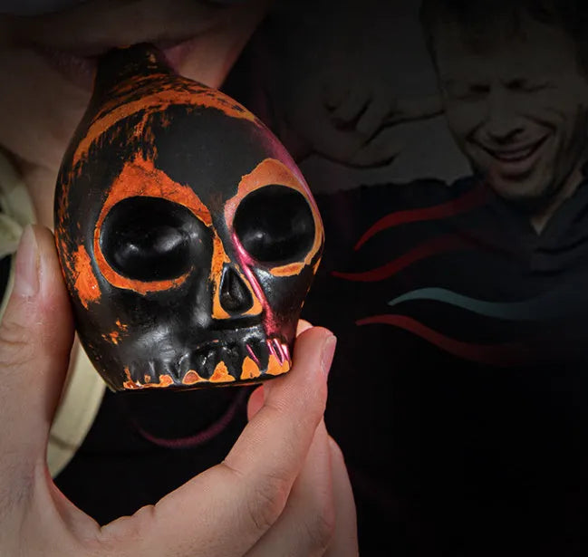 Skull whistle decompression toy in dolomite ceramic, shown in matte black and red and black colour options
