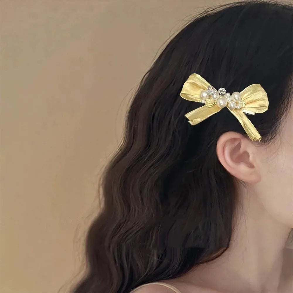 Yellow bow hair clip with rhinestone pearl accents and duckbill clip design