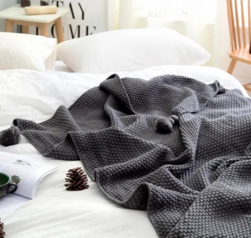 Nordic style fringed acrylic blanket in beige, measuring 130 by 170 centimetres, draped over a sofa.