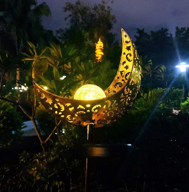 LED solar flame light with warm white glow in a garden, featuring iron and glass construction and stake stand