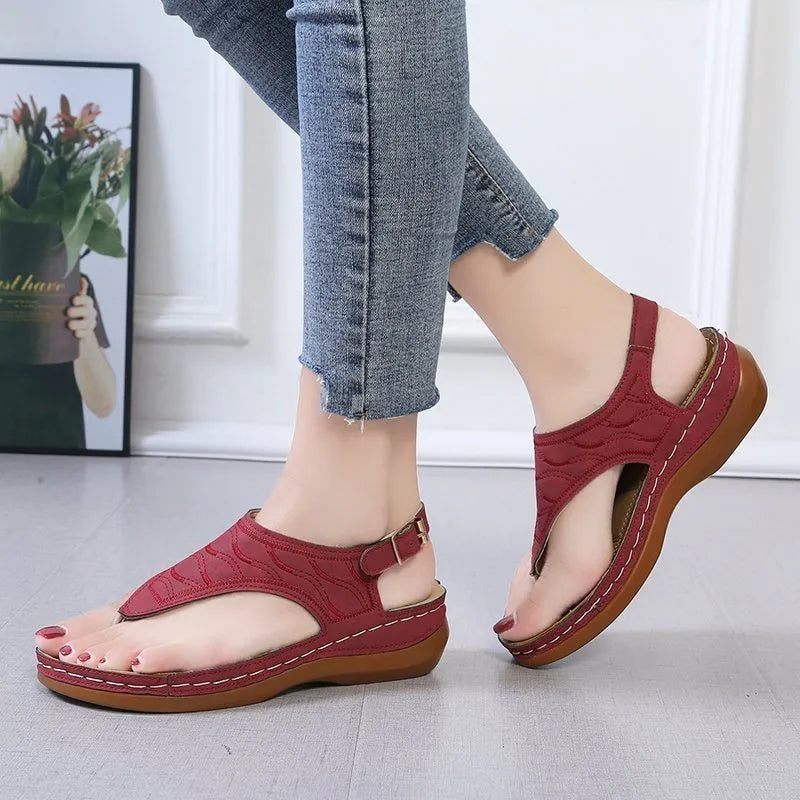 Women's red wedge heel sandals with an adjustable buckle strap on a plain background.