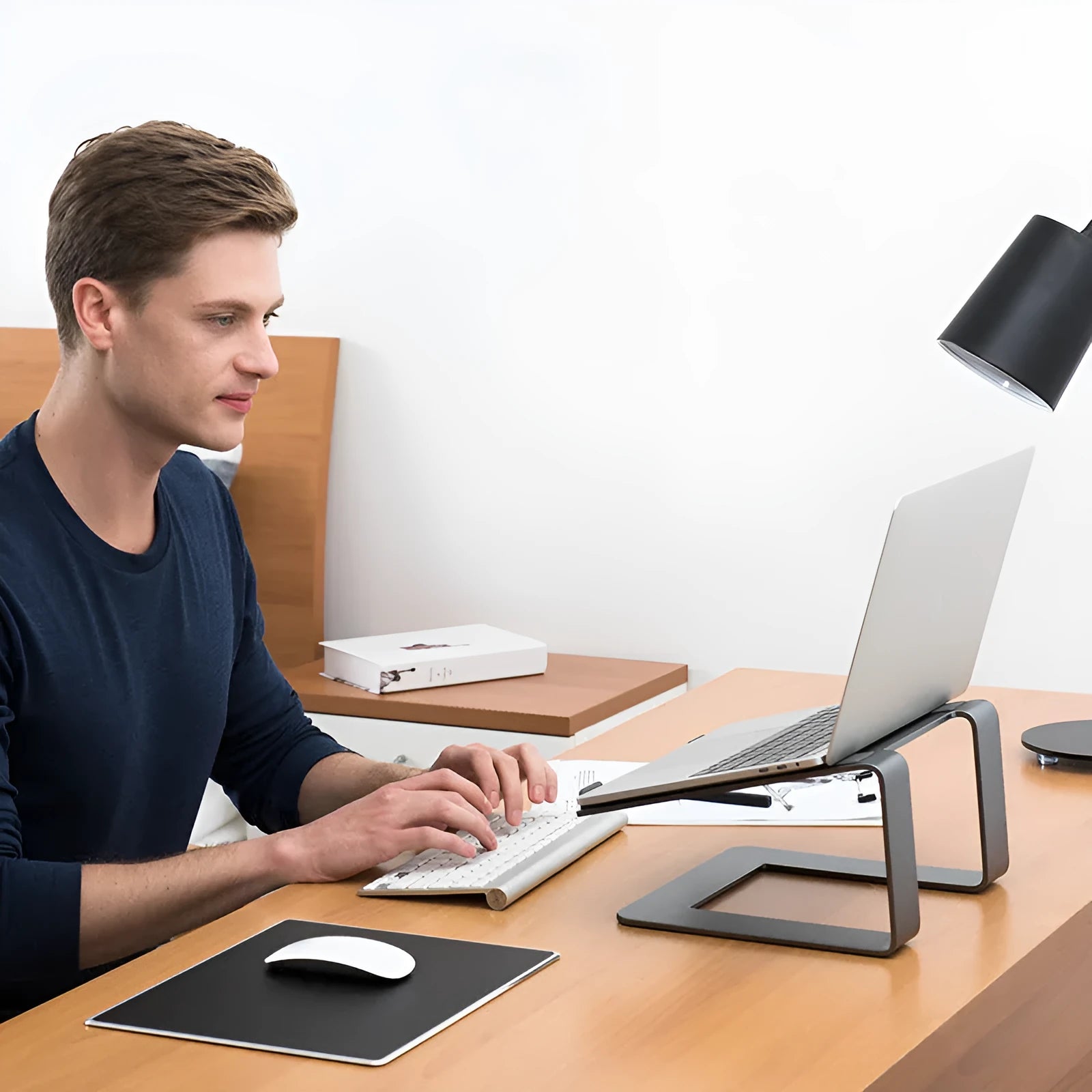 Black aluminium alloy laptop stand on wooden desk with laptop positioned on top