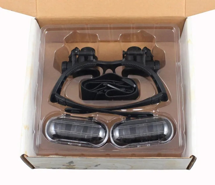 Black hands-free LED magnifying glasses with interchangeable lenses on a headband for watch repair.