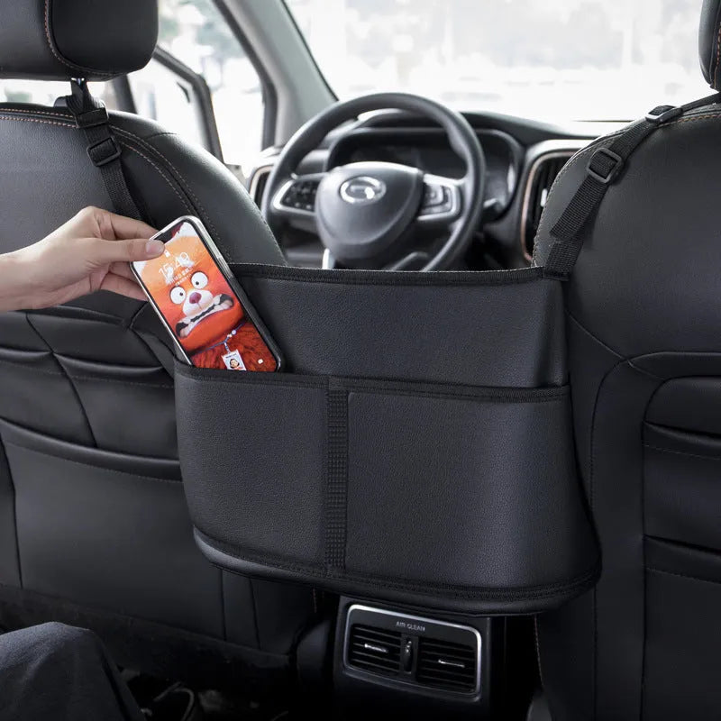 Black leather car seat storage bag with carbon fibre pattern, shown fitted in a car seat net pocket.